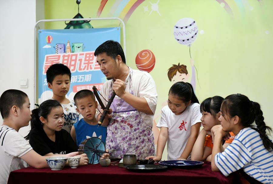 Li Junhang teaches local students the craftsmanship of porcelain restoration in Shijiazhuang, Hebei Province, Aug. 8, 2018. (Photo/Xinhua)