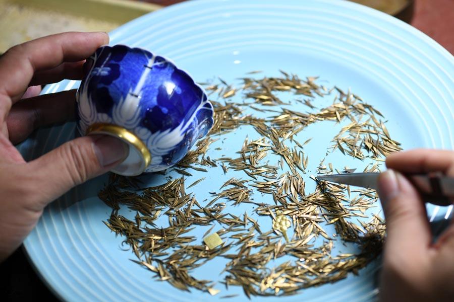 Li Junhang picks a suitable nail for a broken porcelain bowl, at his studio in North China\'s Hebei Province, Aug. 6, 2018. (Photo/Xinhua)