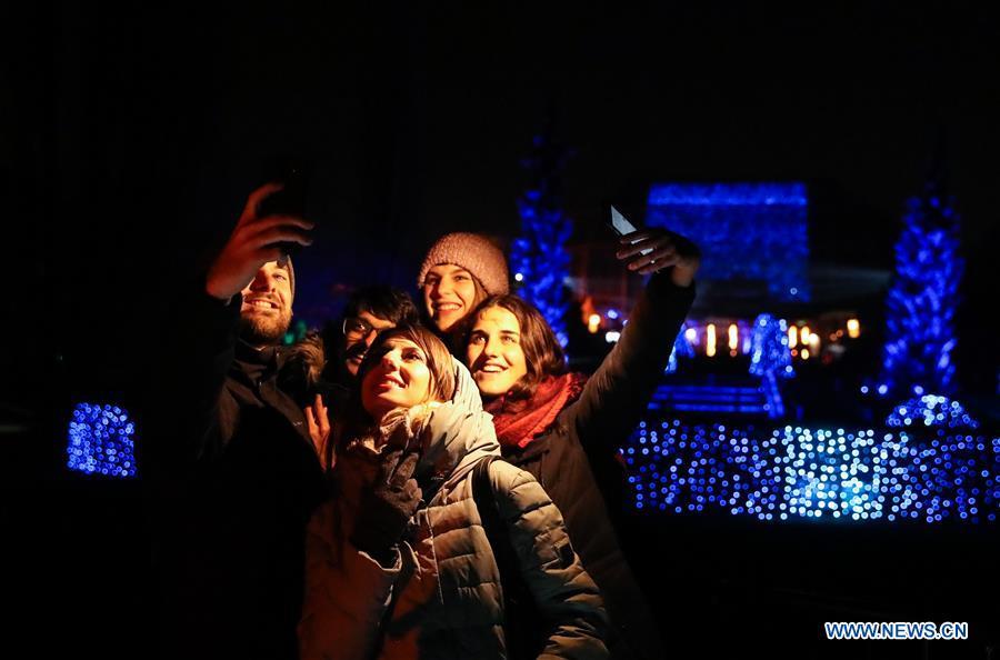 Visitors take selfies in front of light decorations during the \