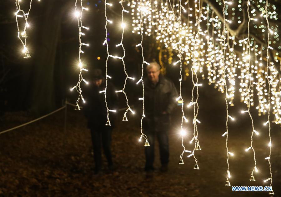 Two visitors walk under light decorations during the \