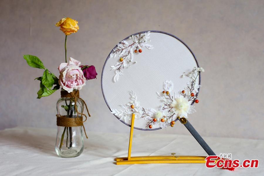 Liu Yao, a girl from northwestern China city Lanzhou, shows her embroidery works featuring patterns made of preserved flowers. With stitching techniques of Suzhou Embroidery and beading skills, the girl, an embroidery lover, makes her works with colorful dried flowers. (Photo: China News Service/ Gao Zhan)