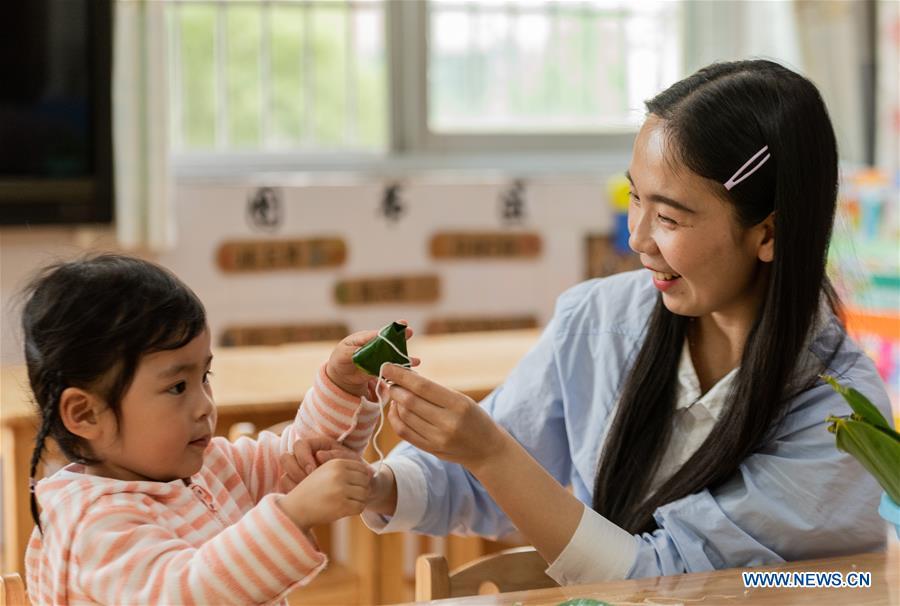 A woman and a child make Zongzi, a kind of rice dumpling wrapped up with bamboo leaves, as part of the traditional folk customs to celebrate the upcoming Duanwu Festival in Zigui County of Yichang, central China\'s Hubei Province, May 29, 2019. Duanwu Festival is traditionally celebrated on the fifth day of the fifth month on Chinese lunar calendar. (Xinhua/Zheng Jiayu)